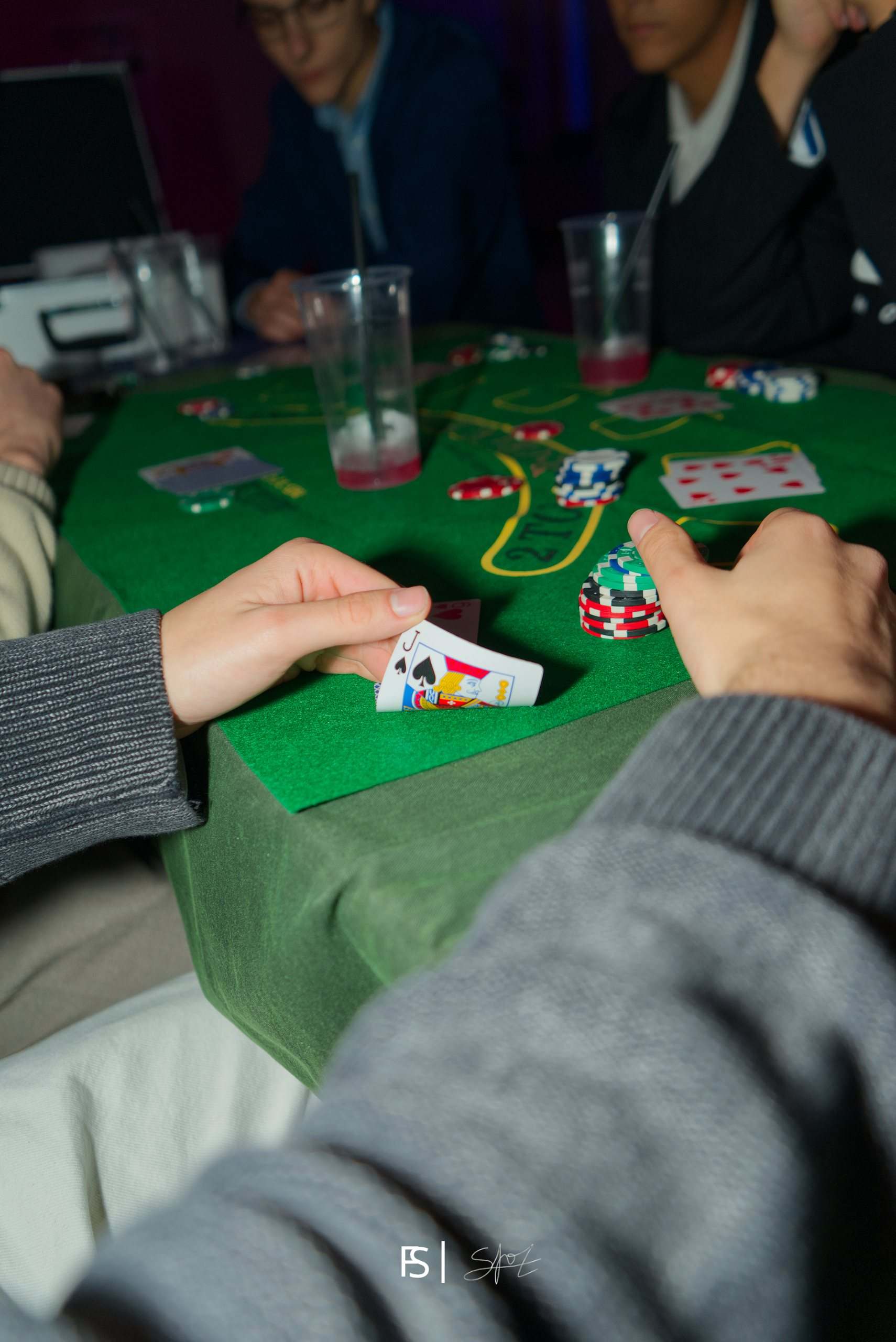 Mani che scoprono le carte sul tavolo verde tra fiches colorate