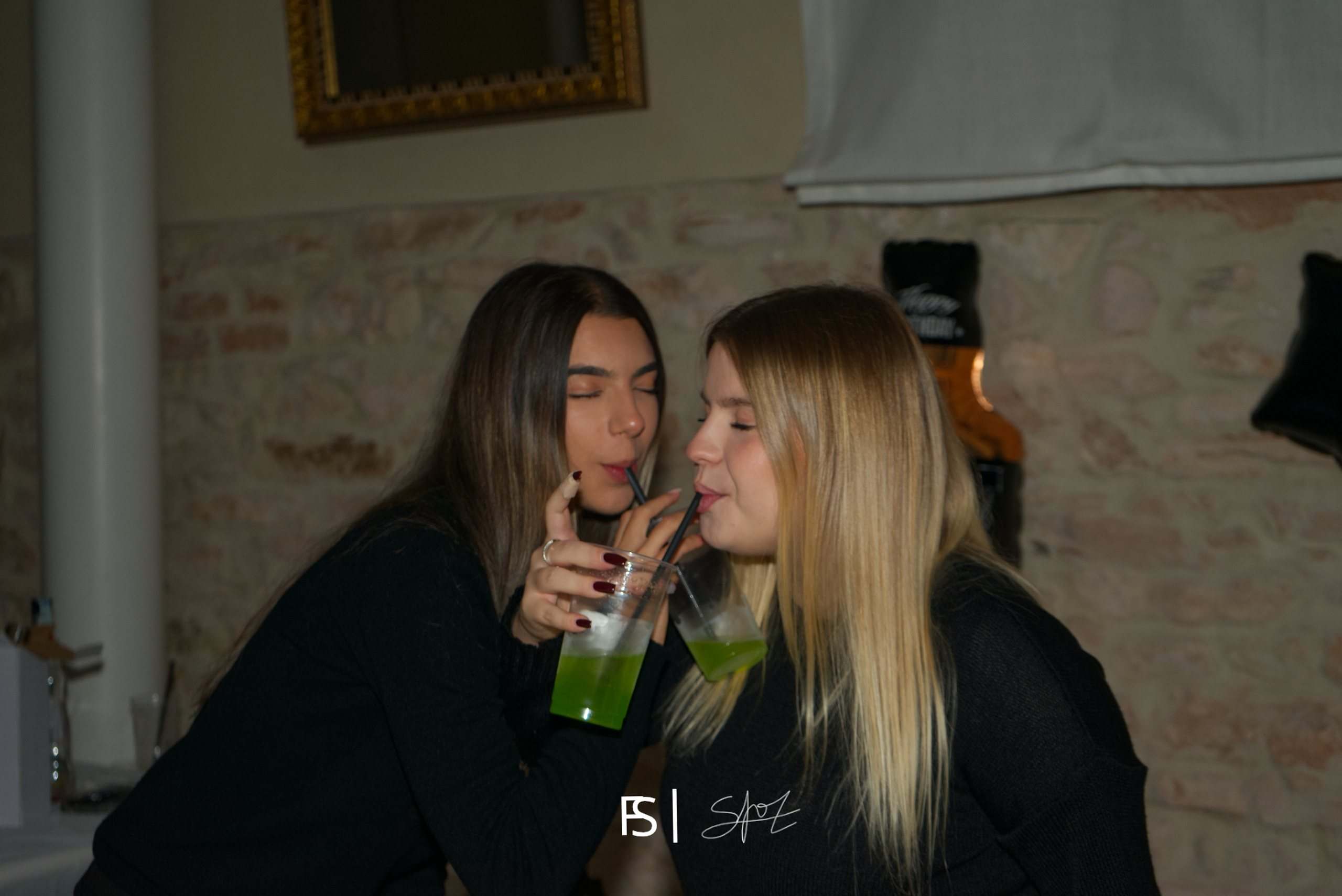 Due amiche vicine che bevono cocktail verdi con la cannuccia