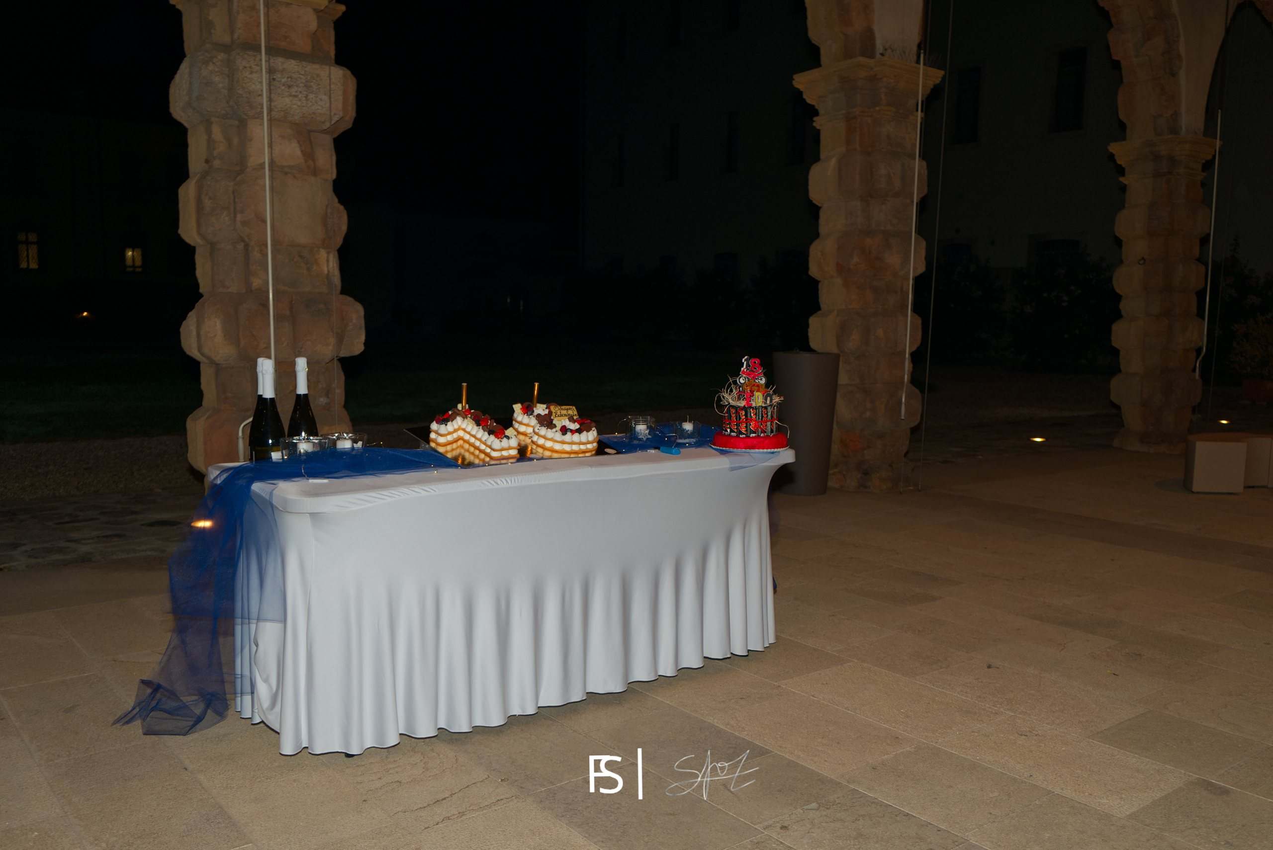 Tavolo con le torte sotto il porticato di notte, tra le colonne in pietra