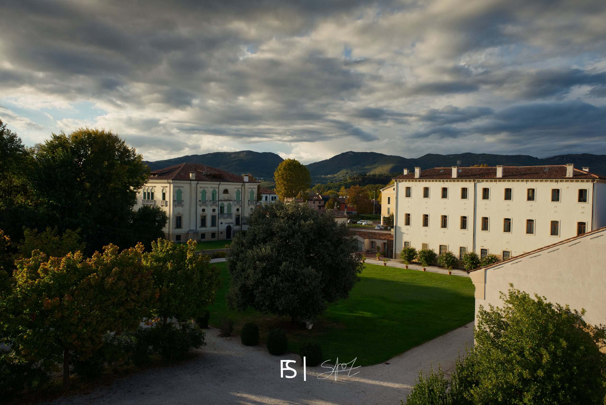 La villa e il parco visti dall’alto, con le colline e un cielo carico di nuvole